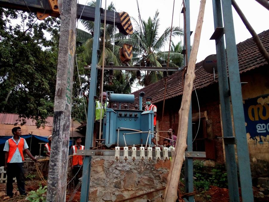 Transformer being positioned on a double-pole structure with crane and site crew